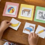 Kindergarten child sorting handmade Filipino beginning-sound picture cards on a wooden table